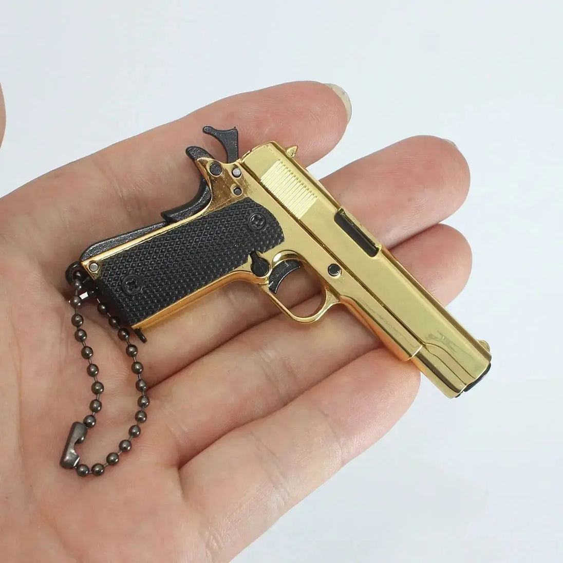 1:3 1911 Scale Handgun - Gold miniature die cast metal handgun with black grips held in hand.