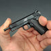1:3 1911 Scale Handgun - Black miniature die cast metal model with functional safety and slide held in hand.