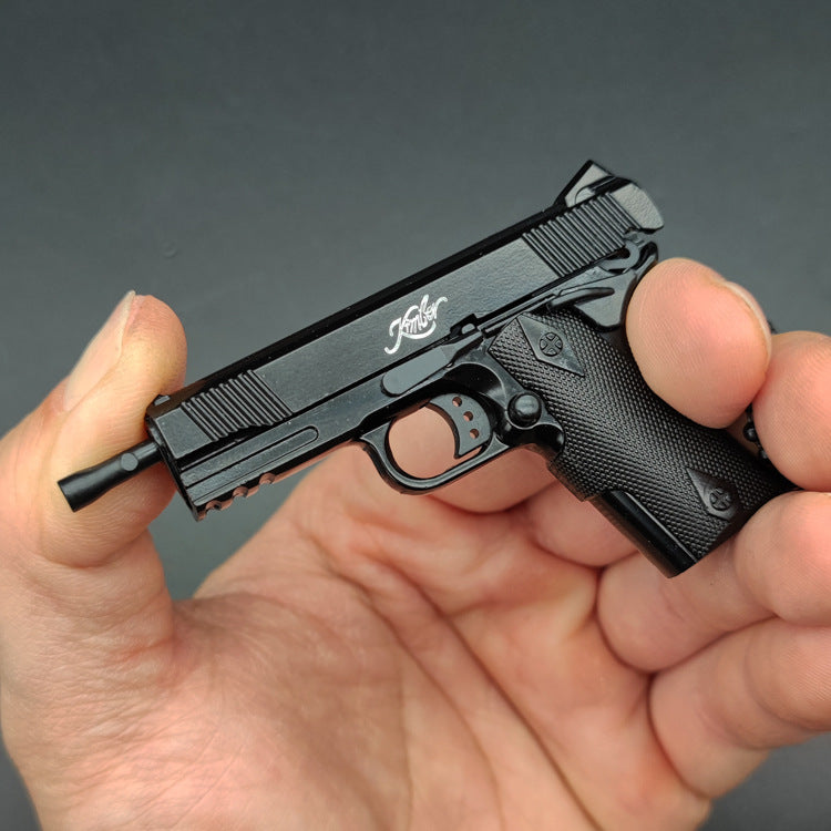 1:3 1911 Scale Handgun - Black miniature die cast metal model with functional safety and slide held in hand.