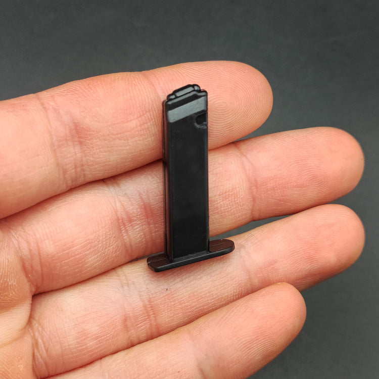 Magazine for the 1:3 1911 Scale Handgun - Black shown held between fingers on a dark background.