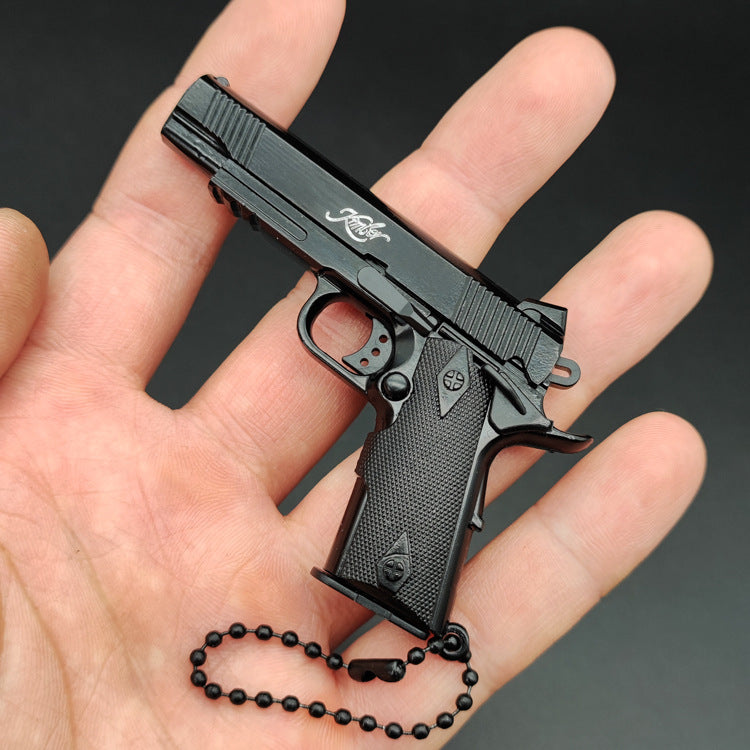 1:3 1911 Scale Handgun - Black die cast metal miniature with working safety and slide held in hand with black chain.
