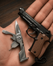 Pistool and multi-tool on a hand with wooden background
