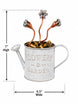 A decorative metal watering can garden ornament with embossed 'FLOWERS & GARDEN' text, filled with small flower buds and stems, shown with dimension arrows indicating 7 inches high and 6.5 inches wide on a white background.