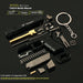 A 1:13 scale model TTi G34 Battle Master miniature keychain kit, shown in a disassembled state with its various components neatly arranged on a dark reflective surface. The kit includes a black keychain body, a gold-colored barrel, a black textured carrying case, a silver metal keychain, springs, screws, and other mechanical parts.