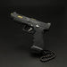 A black semi-automatic pistol with gold accents and a black beaded chain, photographed on a dark black background. The slide features the 'Tactical Tactical' logo.