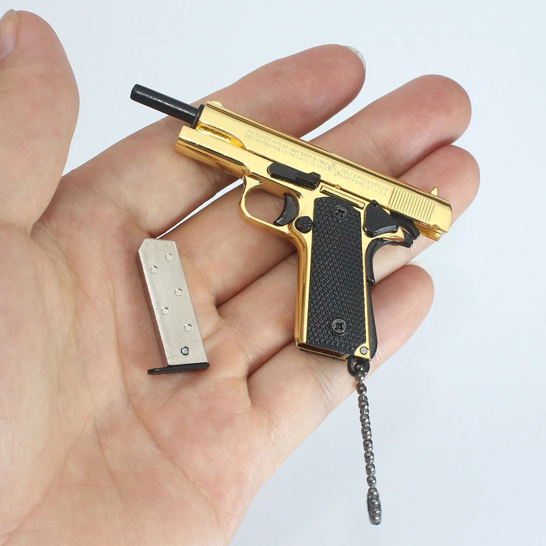 1:3 1911 Scale Handgun - Gold miniature with black grips and detachable magazine held in a hand.