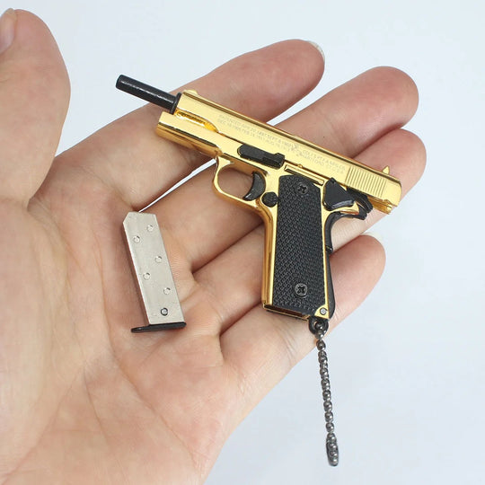 1:3 1911 Scale Handgun - Gold miniature with black grips and detachable magazine held in a hand.