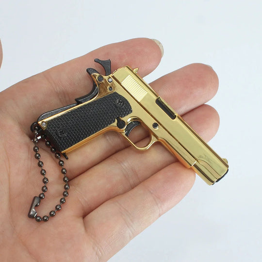 1:3 1911 Scale Handgun - Gold miniature die cast metal handgun with black grips held in hand.